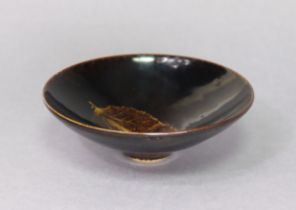 A Chinese Jizhou-style leaf decorated stoneware bowl of conical shape with all-over black glaze,