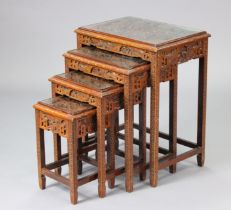 A mid-20th century Chinese hardwood nest of four occasional tables with carved figure scene