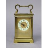 A late 19th/early 20th century brass carriage timepiece, the gilt dial with black Arabic numerals to