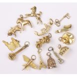 A collection of fifteen various pendant bracelet chrms; three 9ct gold (bird in cage, veteran