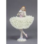 A Sitzendorf porcelain figure of a ballerina, holding a fan to her face, on gilt decorated plinth