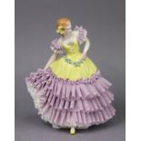 A Sitzendorf porcelain figure of a female dancer, holding a floral garland around her waist. 23cm