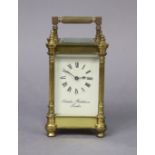 A brass carriage timepiece with round fluted corner columns, the white enamel dial with black