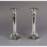 A pair of modern silver candlesticks with plain round columns & on slightly conical circular