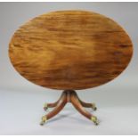 A regency mahogany oval dining table, the tilt-top on a turned centre column & four reeded splay