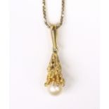 A 9ct. gold abstract “dripping wax” pendant set cultured pearl of approx. 7.5mm dia., on a 9ct