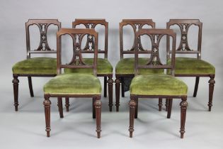 A set of six mid-Victorian walnut dining chairs, the square gothic open backs centred by a