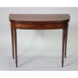 A regency inlaid mahogany bow-front card table with hinged fold-over top, on slender turned tapering