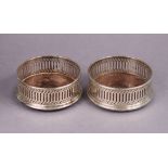 A pair of modern silver wine coasters with pierced straight sides, each inset turned wood base,