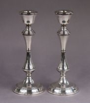 A pair of modern silver candlesticks with slender round waisted columns on circular loaded bases,