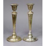 A pair of Edwardian silver candlesticks with round tapered columns & reeded rims, each on loaded