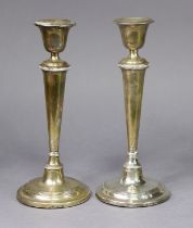 A pair of Edwardian silver candlesticks with round tapered columns & reeded rims, each on loaded