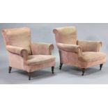 A pair of late 19th/early 20th century upholstered low armchairs, on short turned legs with castors,