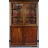 A 19th century mahogany tall cabinet the upper part with two adjustable shelves enclosed by a pair