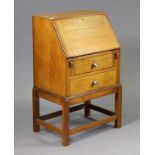 A mid-20th century small oak bureau with a fitted interior enclosed by a fall-front above two long
