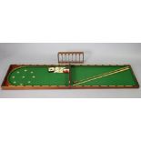 A late 19th/early 20th century mahogany folding table-top bagatelle board (split to top, inset green