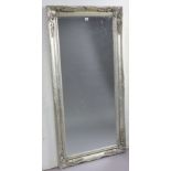 A large rectangular wall mirror in a silvered composition frame; & inset with a bevelled plate,