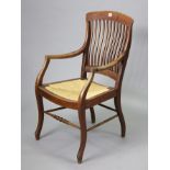 An early 20th century beech comb-back elbow chair with woven-cane seat, & on shaped legs with a