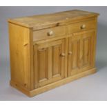 A pine sideboard fitted two frieze drawers above a cupboard enclosed by a pair of panel doors, &