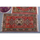 A Persian pattern rug of crimson ground, having multi-coloured geometric design to centre within a