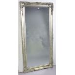 A large rectangular wall mirror in a silvered composition frame; & inset with a bevelled plate,