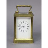 A brass carriage timepiece with all-over engraved scroll decoration, the white enamel dial with
