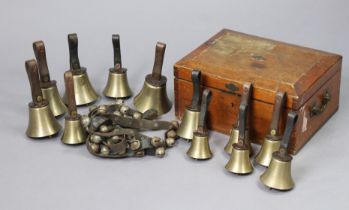 A vintage set of twelve brass hand bells each with a leather handle, & contained in a deal box; &