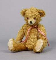 An early/mid-20th century golden plush teddy bear with movable limbs & button eyes, 38cm tall.