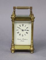 A brass carriage timepiece with round fluted corner columns, the white enamel dial with black