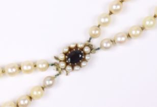 A two-row necklace of graduated cultured pearls, the 9ct gold oval clasp set garnet within a