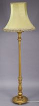 A giltwood standard lamp having a fluted & turned centre column, & on a circular base with bun feet,