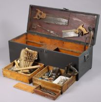 A black painted deal tool-chest enclosed by a hinged lift-lid, & with wrought-iron side handles,