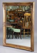 A large gilt frame rectangular wall mirror with a raised scroll border, & inset with a bevelled