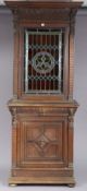 A 19th century carved oak tall cabinet the upper part fitted three shelves enclosed by a leaded
