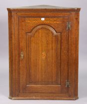 A 19th century inlaid-oak hanging corner cupboard fitted two shelves enclosed by a fielded panel