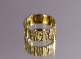 An 18ct. gold wide band with textured finish; size: O; 5.7gm.
