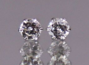 A pair of diamond solitaire ear-studs, each round brilliant-cut stone set to white 18k mounts.