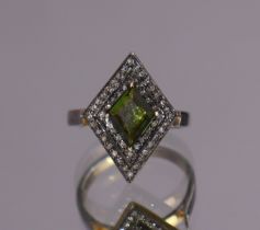 A green tourmaline ring, the kite-shaped stone set within a double border of small rose diamonds, to