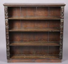 An early 20th century oak open bookcase with applied earlier carvings to the upright supports,