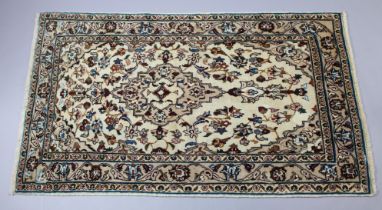A Persian Kashan rug of ivory ground with a central medallion surrounded by floral designs in narrow