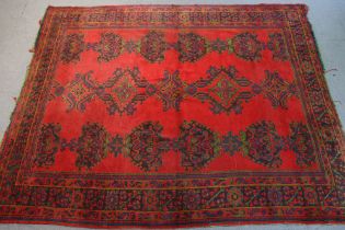 An antique Persian carpet of madder ground, with repeating rows of geometric designs in a wide