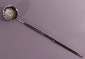 A late 18th century punch ladle, the circular bowl formed from a silver coin, embossed with