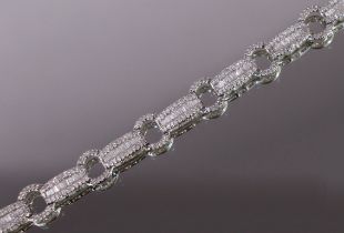 A DIAMOND BRACELET comprised of alternating oval & bowed rectangular links set graduated baguettes &