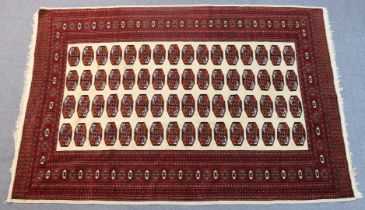A Turkoman bokhara rug of madder ground, the central ivory field with four rows of guhls, in