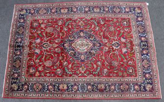 A Tabriz carpet of madder ground, with central medallion surrounded by floral spandrels, in multiple