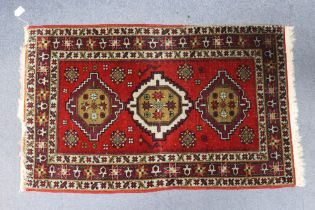 An antique Persian rug of madder ground, with central row of three medallions surrounded by