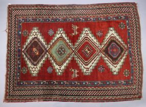 An antique Persian rug of madder ground with a central row of four lozenges in ivory and green,