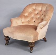 A Victorian low armchair with rounded buttoned back upholstered salmon-pink velour, on short