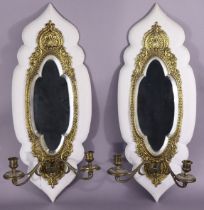 A pair of late Victorian brass repousse girandoles, of elongated oval shape, inset bevelled mirror