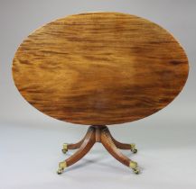 A regency mahogany oval dining table, the fixed top on a turned centre column & four reeded splay